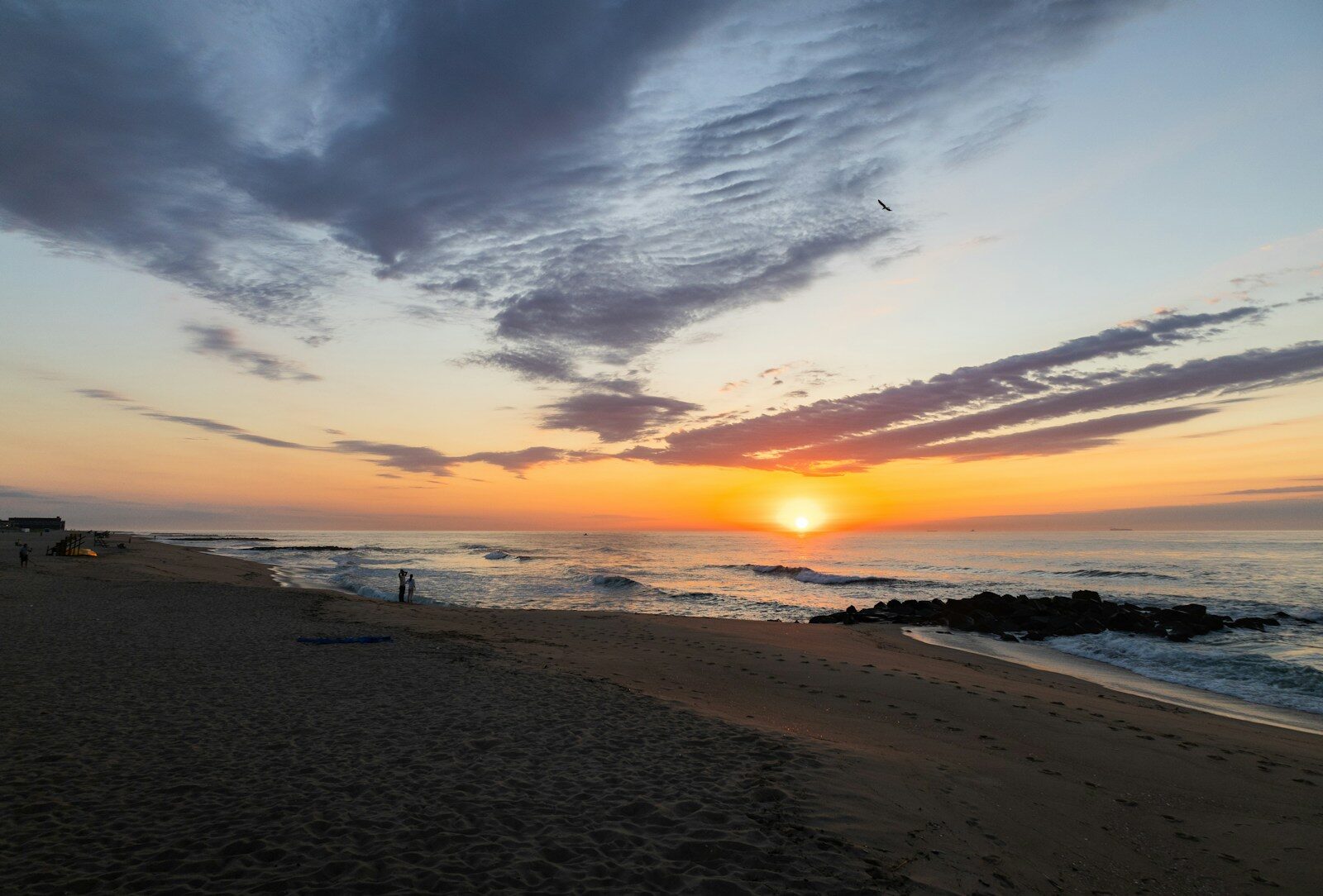 the sun is setting over the ocean on the beach